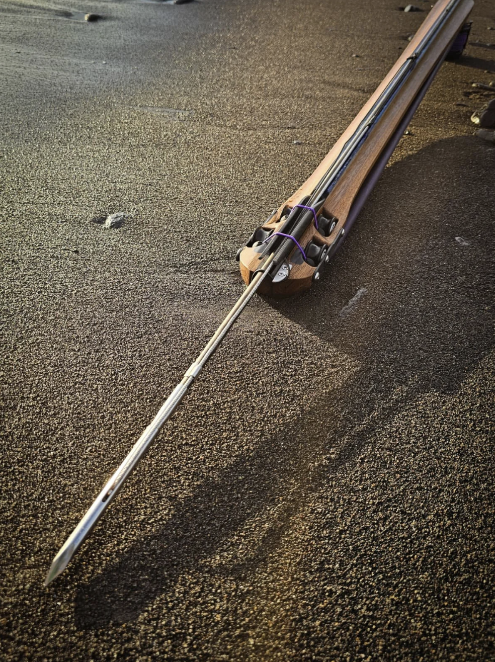 Handcrafted speargun on dark sand